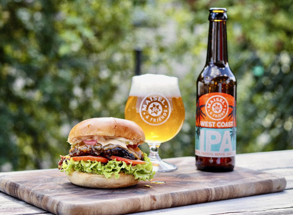 A Burger And Beer On A Cutting Board